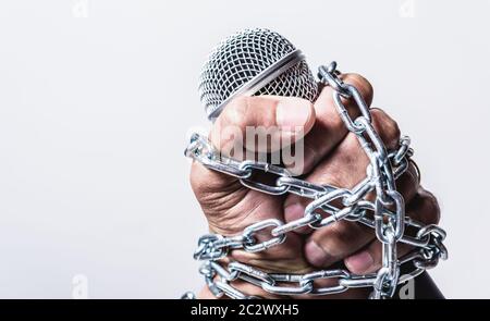 Hand holding microphone and have chain on fist hand on white background, Human rights day concept Stock Photo