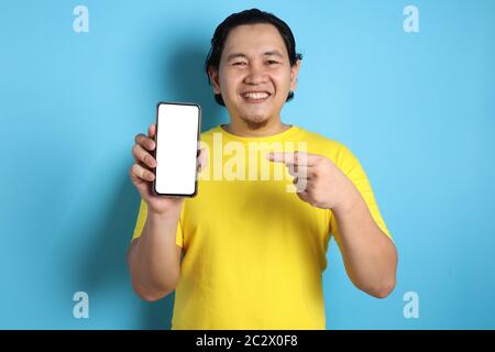 Portrait of young young Asian man presenting smart phone mockup with selective focus Stock Photo