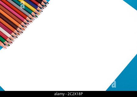 Colored pencils in a row. White sheet of paper on a blue background. Copy space Stock Photo