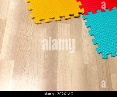 Soft rubber mat composed of colored blocks intersected with each other on a wooden floor. Suitable for children to play or for yoga exercises. Interio Stock Photo