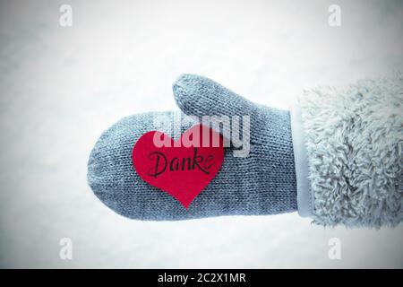 Red Heart With German Calligraphy Danke Means Thank You. Human Hand In A Glove With Fleece And Snow. Stock Photo