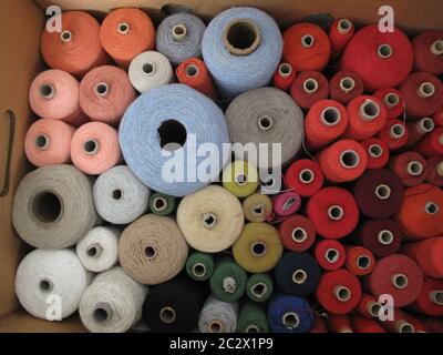 large group of fine cotton and linen yarns in in the colors red, salmon, white, beige, smoke grey, brown, light blue, green, orange, wine red, black e Stock Photo