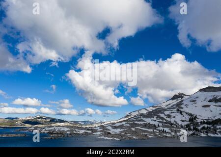 Snowmelt has filled a high mountain lake in the Sierra Nevada mountains in California. These scenic mountains rise between 5,000 and 9,000 feet high. Stock Photo