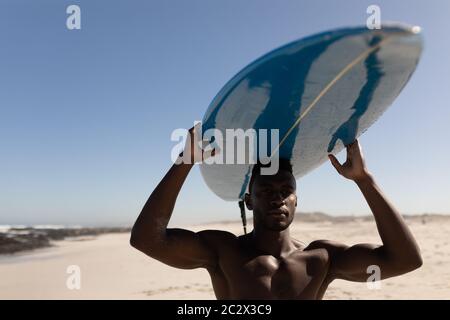 African American man holding surf board on the beach Stock Photo