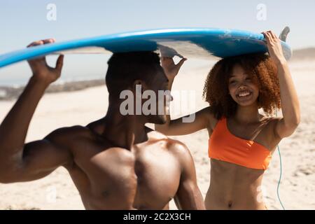 Mixed race couple holding surf boards on the beach Stock Photo