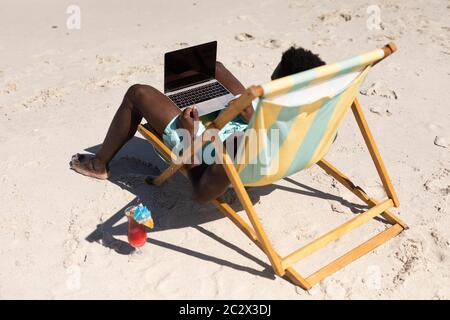 African American man using computer on the beach Stock Photo