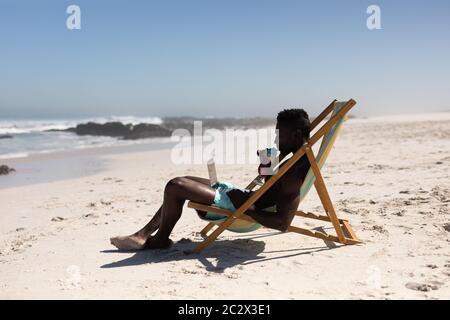 African American man using computer on the beach Stock Photo