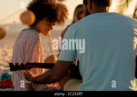 Mixed race friends group playing guitar on beach Stock Photo