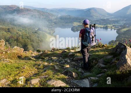 Walker Enjoying the View over Grasmere Lake from Loughrigg Fell on a Misty Summer Morning, Lake District, Cumbria, UK Stock Photo