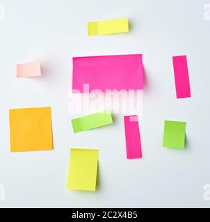 various blank paper multicolored stickers on a white wall, close up Stock Photo