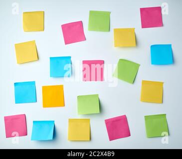 lot of blank square paper multicolored stickers on a white wall, close up Stock Photo