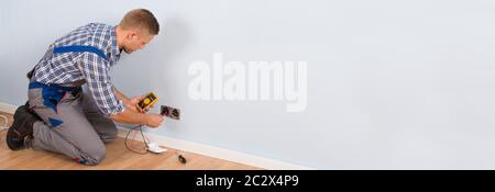 Male Electrician Checking Voltage Of Socket With Multimeter In House Stock Photo