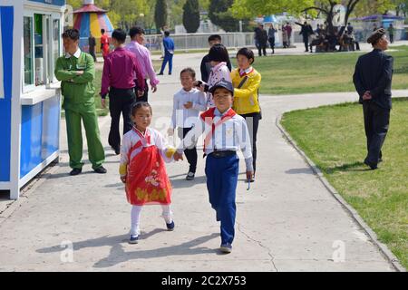 Pyongyang, North Korea - May 1, 2019: Young boy, member of the Young Pioneer Corps and his little sister in national korean dress on a city street Stock Photo