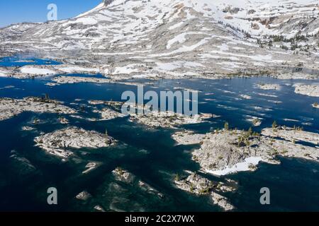Snowmelt has filled a high mountain lake in the Sierra Nevada mountains in California. These scenic mountains rise between 5,000 and 9,000 feet high. Stock Photo