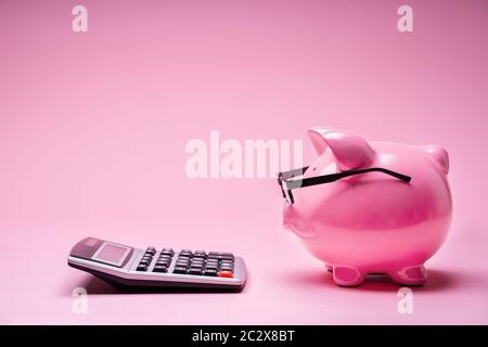 Piggybank Wearing Glasses And Calculator On Pink Background Stock Photo