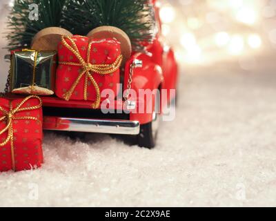 Red Christmas truck with Christmas trees and gift boxes in the snow, selective focus on the foreground, space for your text on the right side Stock Photo