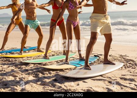 Multi-ethnic group of male and female, surfing on the beach