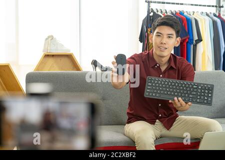 Young asian male online merchant blogger using smart mobile phone to recording live vlog video for review IT product goods. Online influcencer on soci Stock Photo
