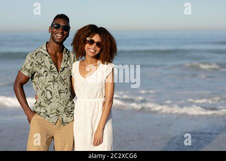 A mixed race couple posing and smiling on beach on a sunny day Stock Photo
