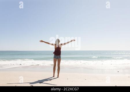 Young caucasian woman raising arms on the beach Stock Photo