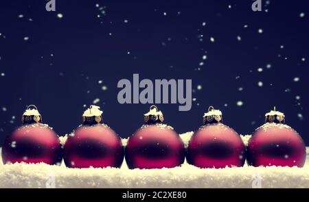 Old used red Christmas baubles with snow on a dark background Stock Photo