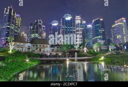 Downtown Jakarta skyline with green view and river in the night Stock Photo