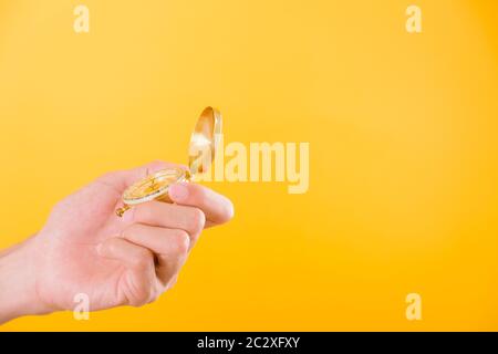 Hand holding antique brass compass isolated on yellow background with copy space for text Stock Photo