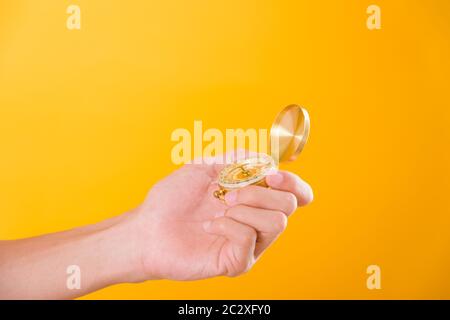 Hand holding antique brass compass isolated on yellow background with copy space for text Stock Photo