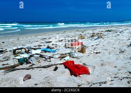 Plastic bottles and other rubbish thrown on the sandy seashore, trash on the sea beach. ecological problem. Environmental pollution. Dirty sandy beach Stock Photo