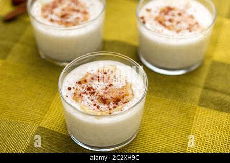 Coconut flavored rice pudding dessert with maple sirup drizzle on top and sprinkled cinnamon served in glass bowl. Stock Photo