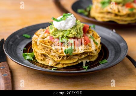 Crunchy chicken tostada stack. Tostadas are a type mexican food, made with crispy fried corn tortillas covered with layers of various ingredients. Stock Photo