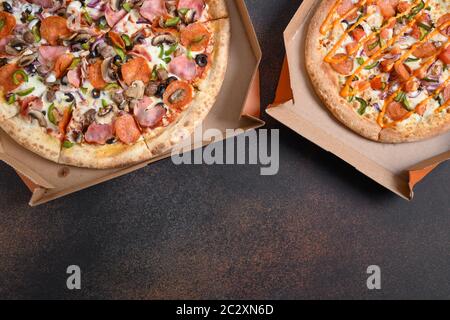 Delivered Italian pizzas with tomato, pepperoni, pepper, Mozzarella cheese. Food pattern. Copy space. Stock Photo