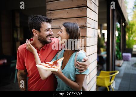 Happy couple laughing and eating pizza, having fun together Stock Photo