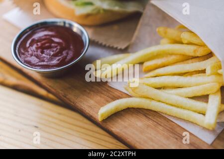 Fresh tasty burger and french fries on wooden table. french fries and bbq sauce on wood plate. street food burger and fried pota Stock Photo