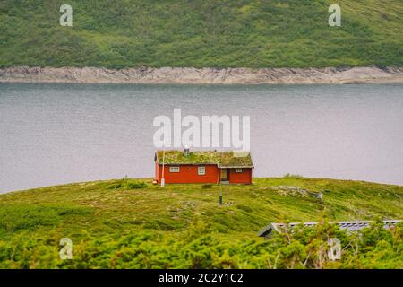Norwegian wooden summer house overlooking scenic lake, Norway, Scandinavia. Cottage By Lake In Rural. Peat roofed hut on Lake. T Stock Photo