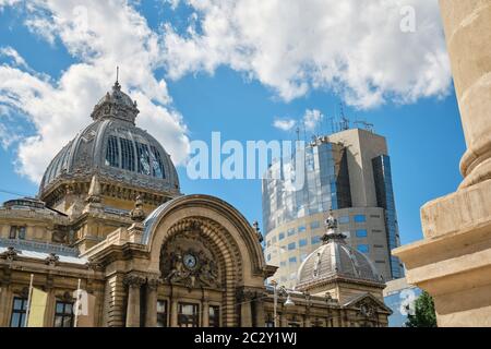 Built in 1900, CEC Palace in Bucharest, Romania (in Romanian: Palatul CEC) next to tall building with clouds reflected in its glass exterior. Popular Stock Photo