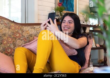 Woman uses her cell phone to make a video call while at home due to coronavirus quarantine Stock Photo