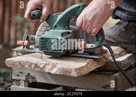 a hand circular saw cuts a board on the street Stock Photo