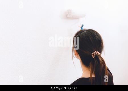 Young woman painting the wall of her house white Stock Photo