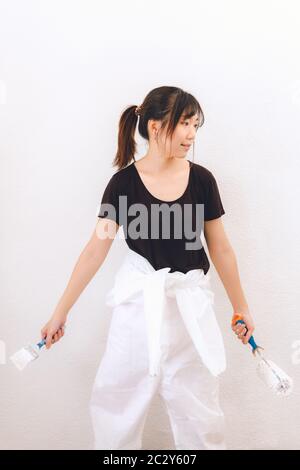 Professional independent woman painter holding brush and roller Stock Photo