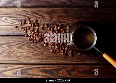 close-up shot of cezve with coffee beans on rustic wooden table top view Stock Photo