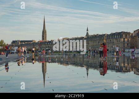 People have fun and refresh on a hot summer day, in the mirror fountain in Bordeaux, France Stock Photo