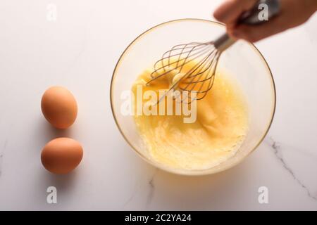 Making of mixing eggs in bowl on marble table as homemade food flat lay, top view food brand photography flatlay and recipe for Stock Photo