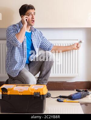 The young repairman contractor repairing heating panel Stock Photo