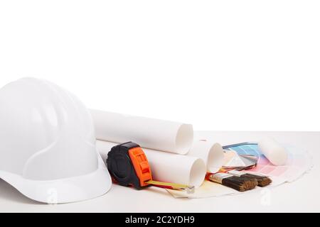 Architectural blueprints, construction hard hat, color palette guide, painting accessories on white background.  Architect workplace. Engineering tool Stock Photo