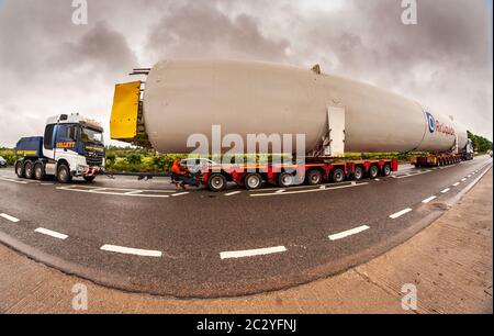 Shenstone, Staffordshire, UK. 18th June, 2020. A supersize oxygen tank - 40m long and 6.5m wide - is on its fourth day or transport across the midlands. Two cabs pulling and pushing, 156 wheels, four drivers, and many police and BT engineers and tree cutters are involved, as the enormous load goes from Cheshire to north Warwickshire. An 8mm fisheye lens just about managed to capture the scene. Credit: Peter Lopeman/Alamy Live News Stock Photo