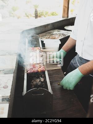 Man cooking the street food many skewers with lamb meat cooked grilled, called arrosticini in Italy. Stock Photo