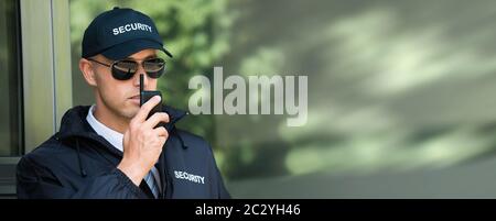 Young Male Security Guard In Black Uniform Using Walkie-Talkie Stock Photo