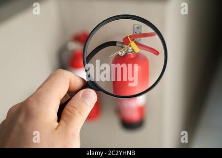 Male Professional Checking The Condition Of A Fire Extinguisher Stock Photo