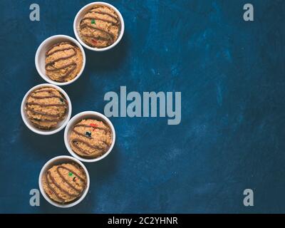 Safe-to-eat raw monster cookie dough in small portion bowl on blue background. Ideas and recipes for kids and toddlers meal. Top view or flat-lay. Cop Stock Photo